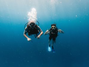 two males doing deep scuba diving in ocean