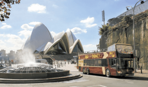 Sydney hop on hop off bus passing by Sydney Opera House