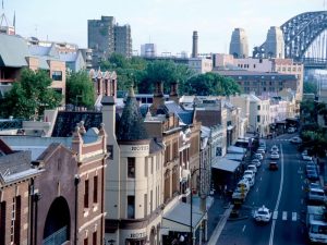 Sydney's The Rocks area with old sandstone buildings overshadowed by the Sydney Harbour Bridge