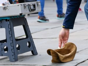 someone putting money in a buskers hat.