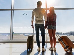 People at airport watching planes take off and land and wondering if their flight will be cancelled due to rising fuel costs.
